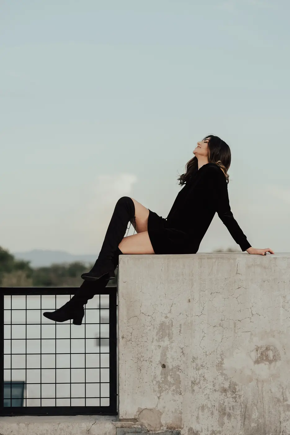 Femme en bottes noires assise sur un muret